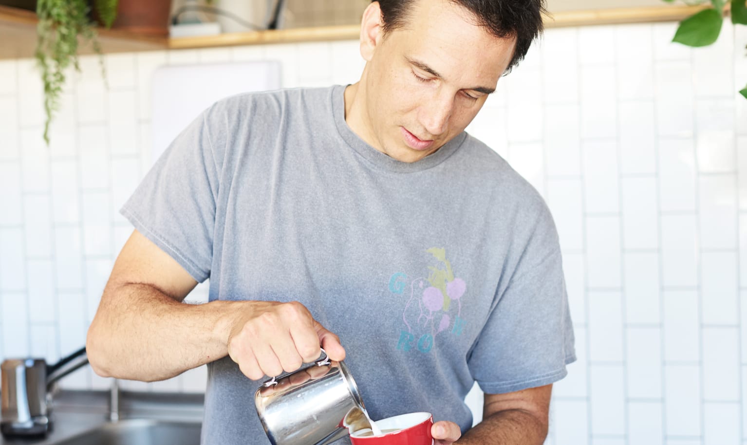 Inhaber Karl von der Rösterei TRYST steht im Laden und macht Latte Art