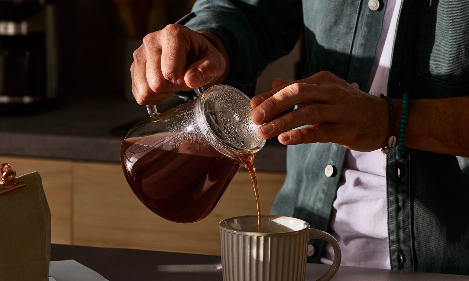 Kaffee wird aus einer Filterkanne in eine Tasse eingeschänkt.
