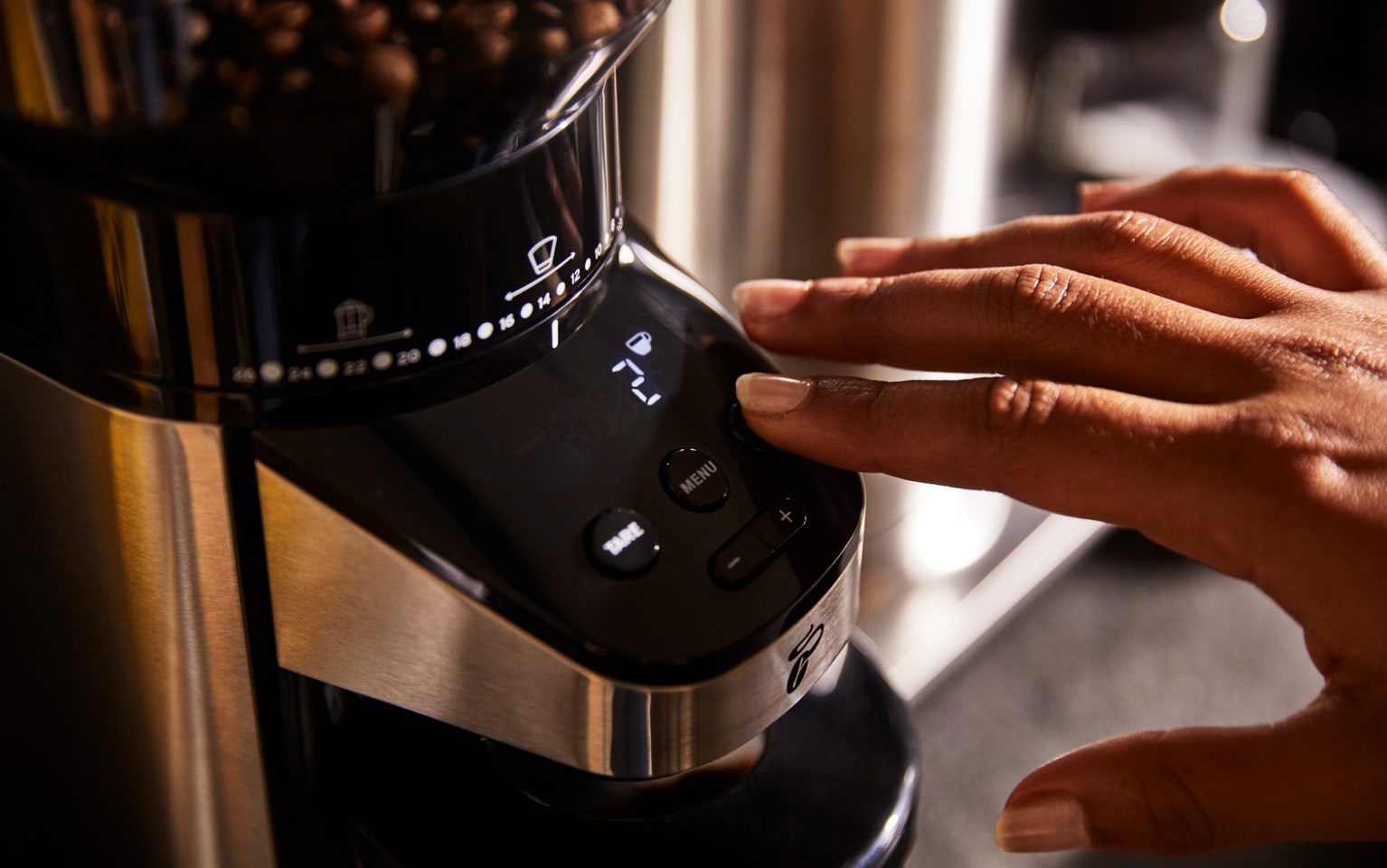 Hand drückt Knopf auf schwarzer Kaffeemühle