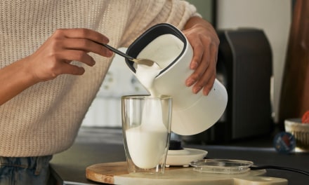 Milchschaum wird aus Milchaufschäumer in ein Glas gegossen