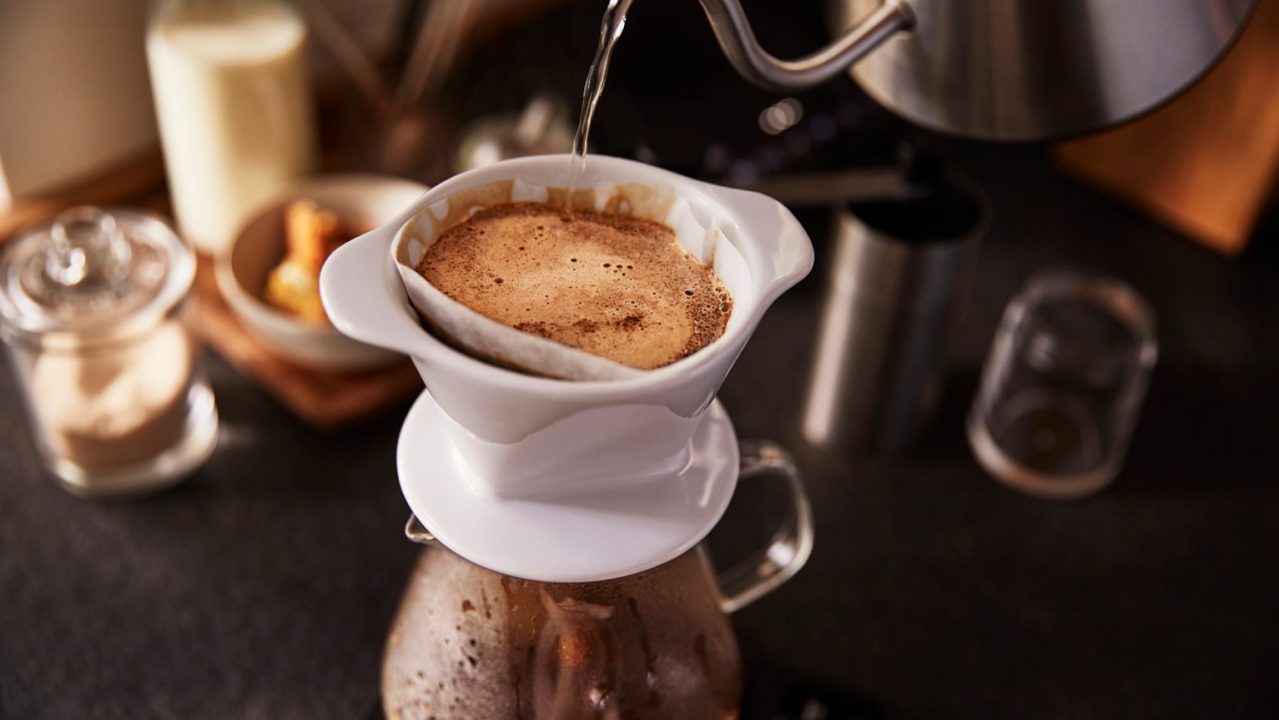Jemand gießt heißes Wasser in einen Kaffeefilter mit Kaffee.
