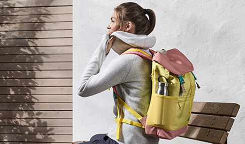 Campingausrüstung für alle Fälle: Eine junge Frau trägt einen Campingrucksack auf dem Rücken der voll gepackt ist.