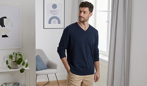 Großartige Basics: Ein Mann trägt einen fein gestrickten dunkelblauen Pullover mit V-Ausschnitt.