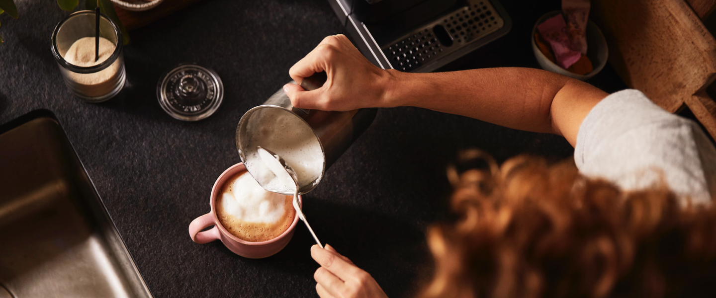 Ein kleines Mädchen schaut freudig und neugierig zu einem Mann hoch, der einen Kaffee trinkt.