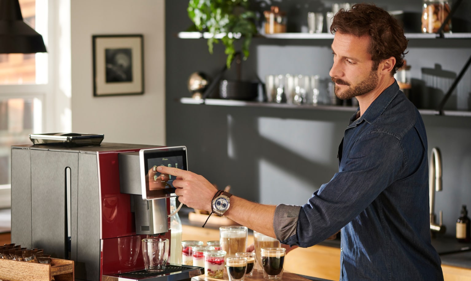 Mann bedient Kaffeevollautomaten in der Küche