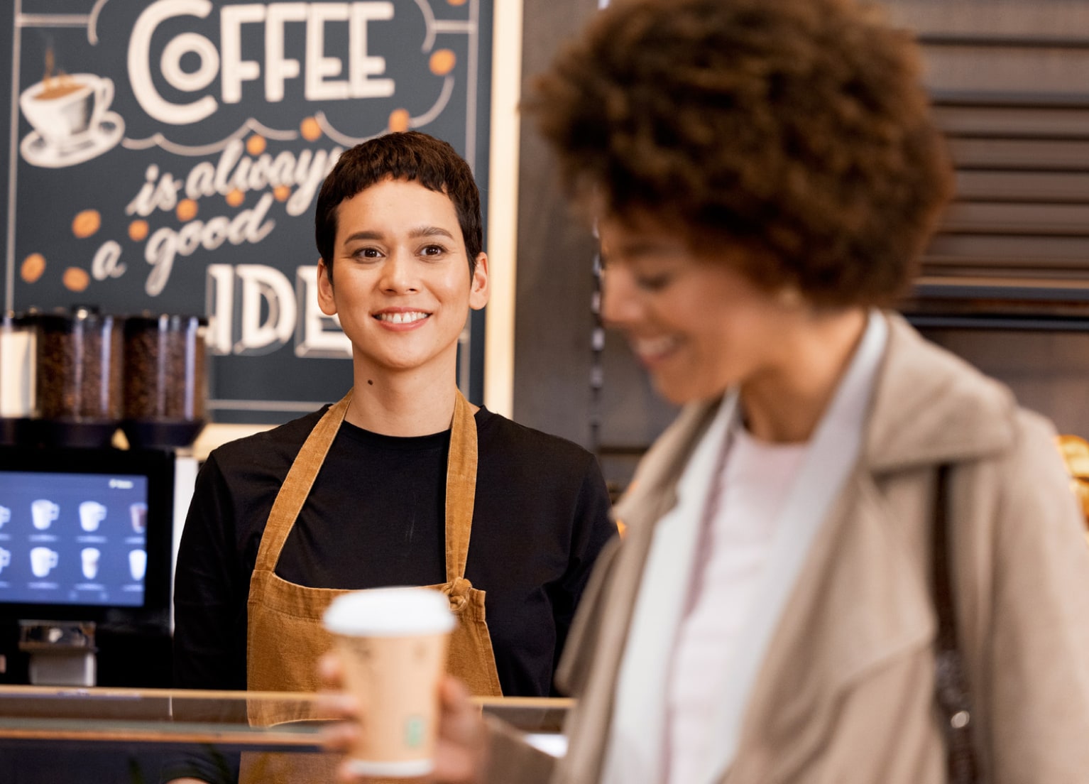 Frau mit To Go Kaffee in Bäckerei