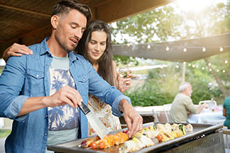Ein Pärchen steht vor dem Grill.