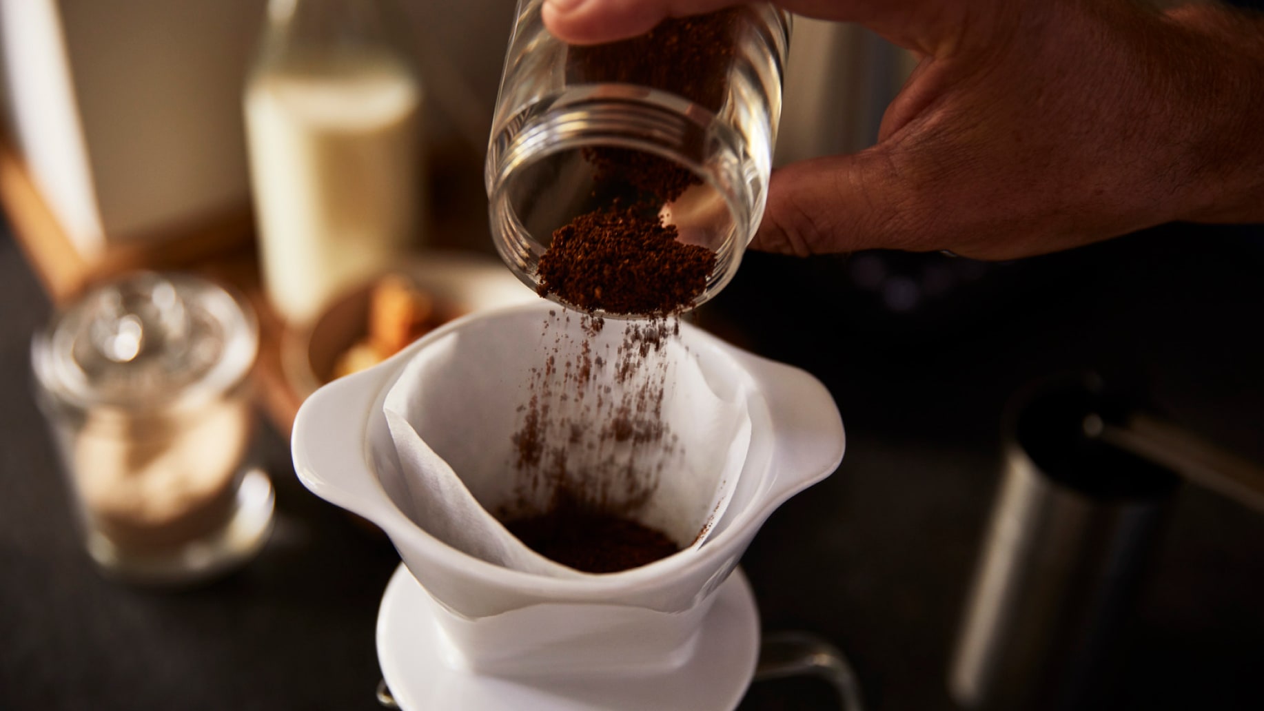 Jemand schüttet gemahlenen Kaffee in eine Filterkanne