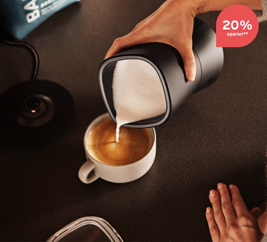Der Schaum aus einem elektrischen Milchaufschäumer wird in den Kaffee gegeben.