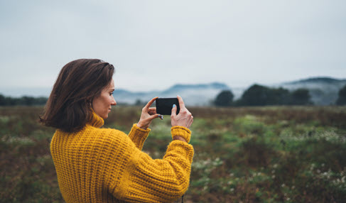 Frau, die mit Smartphone-Kamera ein Bild von der Natur macht.