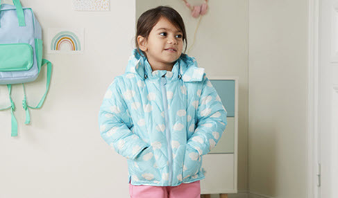 Leichte Pflege: Ein kleines Mädchen trägt eine blaue Winterjacke mit Wolken drauf.