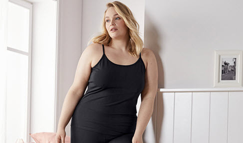 Eine Frau trägt ein schwarzes Sport Top in großer Größe.