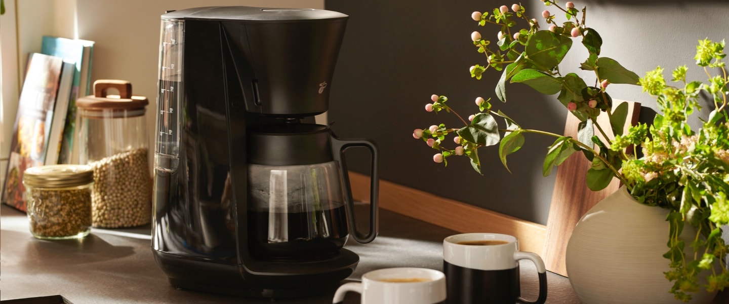 Die Ausprägungen der Tchibo Filterkaffeemaschinen sind auf einem Tresen präsentiert und leiten in die Welt der Filterkaffeemaschinen ein.