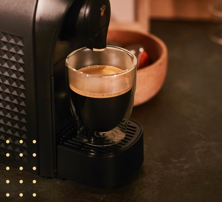 Stimmungsvolles Bild eines Glases Kaffee Crema unter einer Cafissimo Maschine