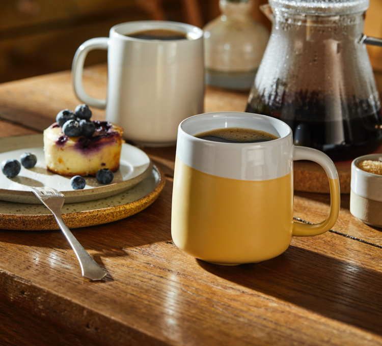 Eine Frau trinkt ihren Kaffee aus einem rosa Kaffeebecher der Porzellanserie.