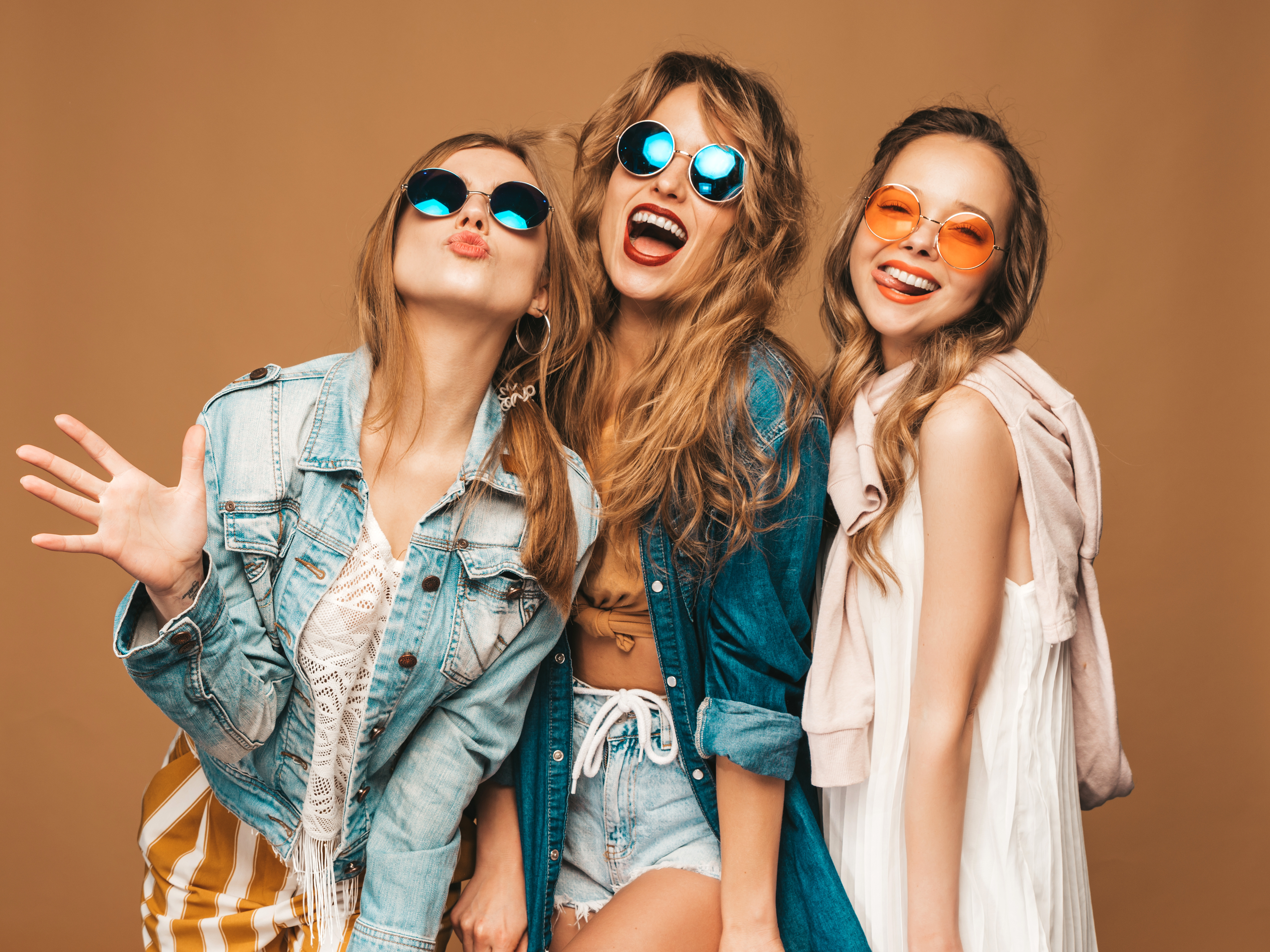 Drei stylische Teenager, die lachend in die Kamera schauen.