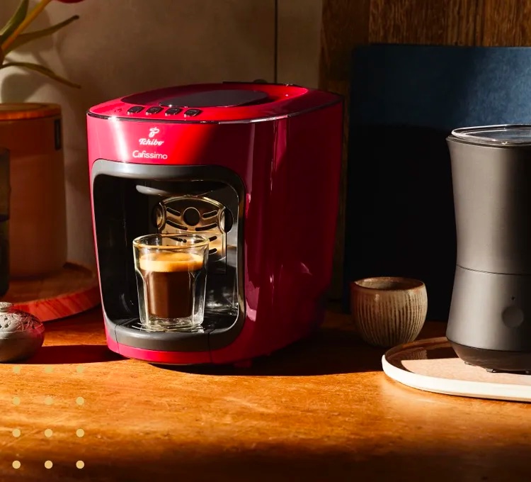 Eine Kapselmaschine in Salsa Red steht auf einer Theke in einer Küche.