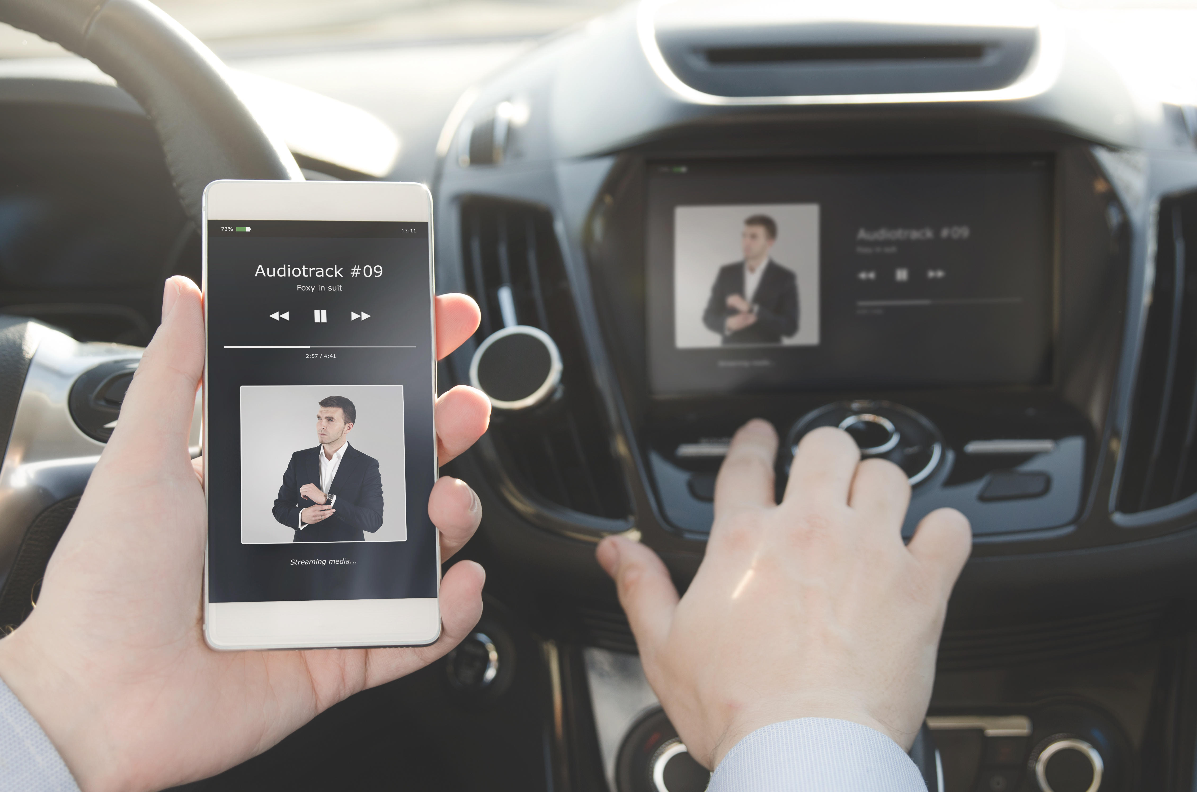 Mann verbindet im Cockpit seines Autos sein Smartphone mit der Musikanlage.