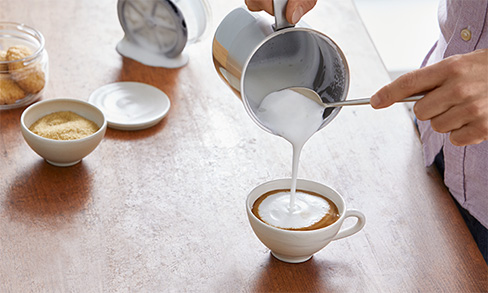 Milchschaum in Tasse gießen