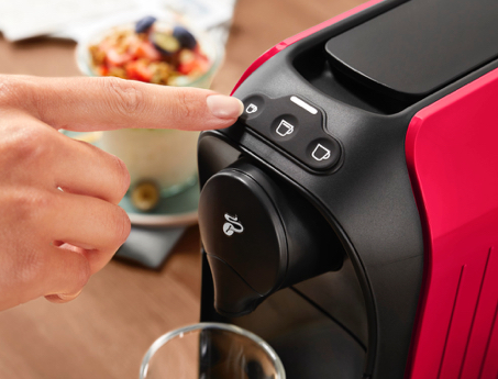 Finger betätigt Espresso Knopf an der weißen Cafissimo easy
