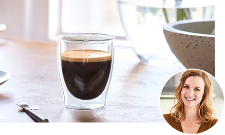 Doppelwandiges Glas mit Kaffee und Bild der Tchibo Kaffee-Sommelière.