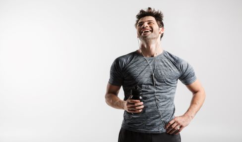 Ein junger Mann trägt zum Laufen gehen ein graues Sportshirt und hört dabei Musik.