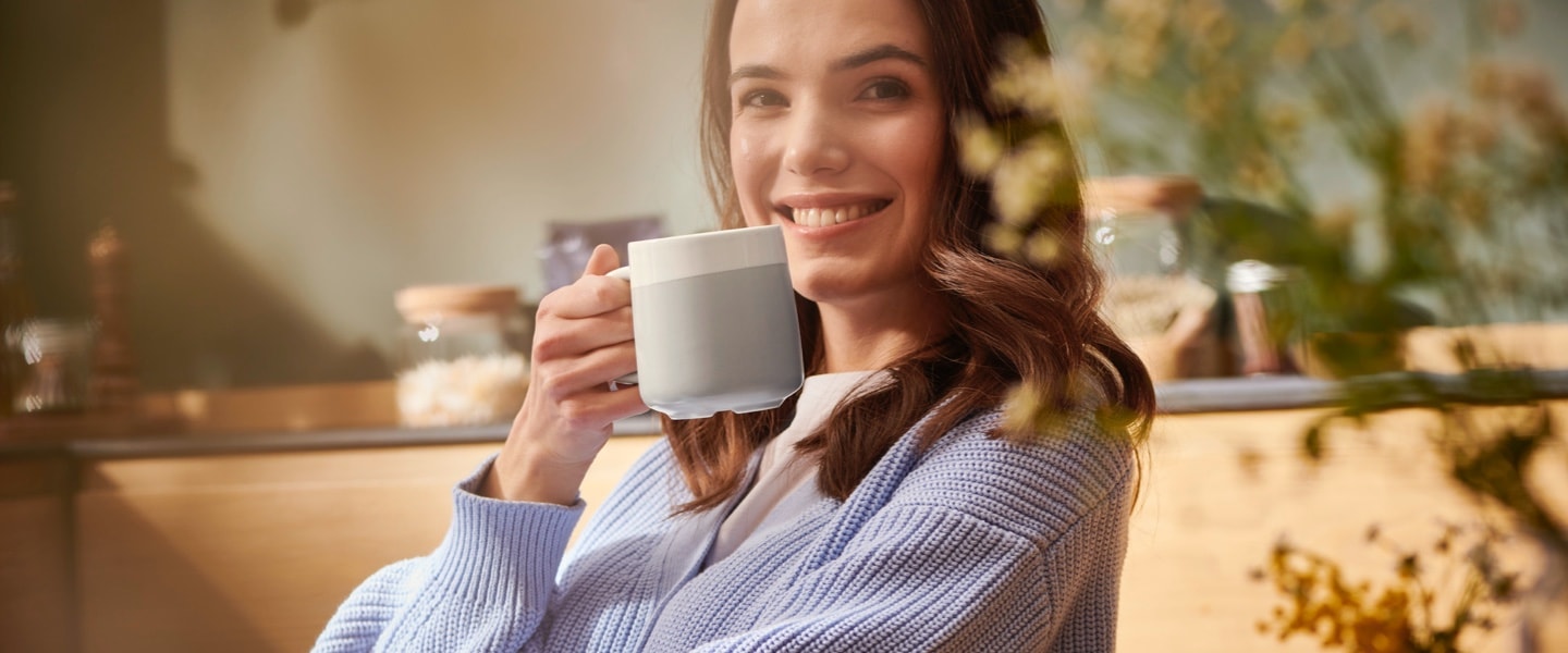 Ein Frau trinkt genüsslich ihren Kaffee aus einem stilvollen Keramikbecher.