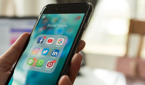 Mann hält Smartphone mit Social Media Apps in den Händen.