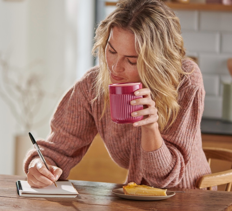 Eine Frau trinkt ihren Kaffee aus einem rosa Kaffeebecher der Porzellanserie.