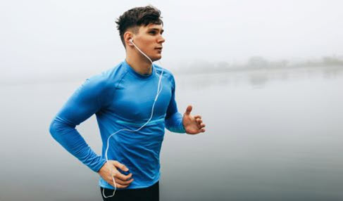 Ein junger Mann geht in einem blauen Langarmshirt joggen.