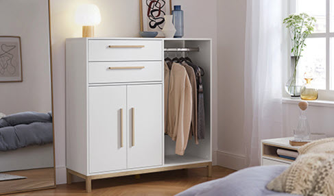 In einem Schlafzimmer ist eine Kommode aus Holz geöffnet.