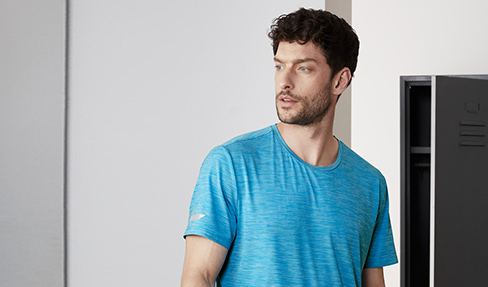 Ein junger Mann in einem blauen Sport-Shirt guckt in die Ferne.