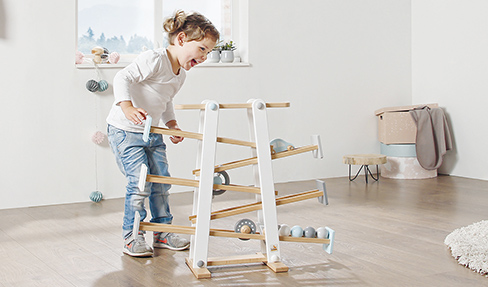Kinderspielzeuge fördern Reize: Ein kleines Kind spielt mit seinem Holzspielzeug im Kinderzimmer.