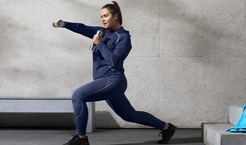 Immer bequem: In ihrer blauen Sport-Leggings in einer großen Größe macht eine Frau draußen Kickbox-Übungen.