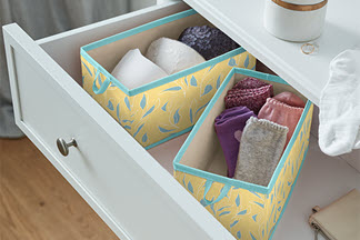 Aufbewahrung im Kleiderschrank: Ein offene Kommode mit zwei Aufbewahrungsbosen, in denen Strümpfe und Unterwäsche verstaut sind.