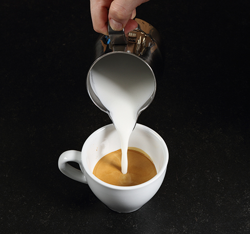 Milch in die Tasse gießen