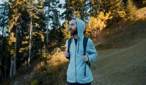 Ein Mann in einer grauen Fleecejacke ist in den Wäldern wandern.