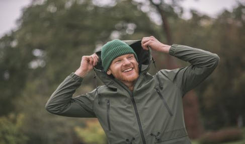 Atmungsaktive Regenjacke: Ein Mann trägt eine dunkelgrüne Regenjacke und eine Mütze.