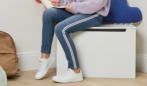 Ein junges Mädchen trägt eine Denim-Hose mit weißen Streifen an der Seite.