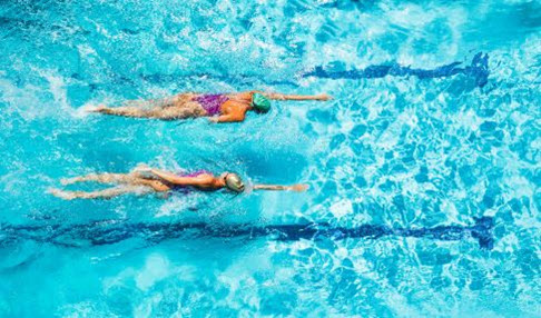 Zwei Frauen ziehen ihre Bahnen in einem Freibad.