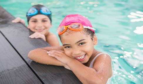 Der Klassiker: Zwei Teenager schwimmen in einem Pool und tragen Badeanzug und Badekappe.