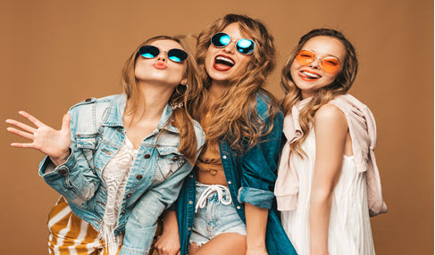 Drei stylische Teenager, die lachend in die Kamera schauen.