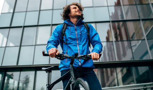 Auch für das Fahrrad geeignet: Ein Mann trägt eine blaue Regenjacke zum Fahrrad fahren.