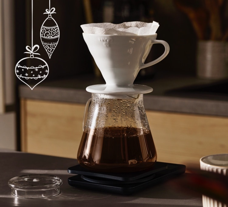 Kaffee läuft durch einen Keramikhandfilter in eine Glaskanne. Dieser Abschnitt befasst sich mit der klassischen Filterzubereitung.