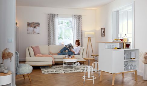 Wohlfühlen durch gute Qualität: Eine Frau liegt auf einem Sofa im Wohnzimmer und liest ein Buch.