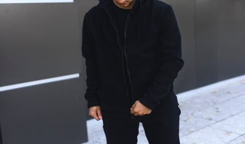 So bleibt die Jacke gut. In einer schwarzen Fleecejacke lehnt sich der Mann gegen eine Hauswand.