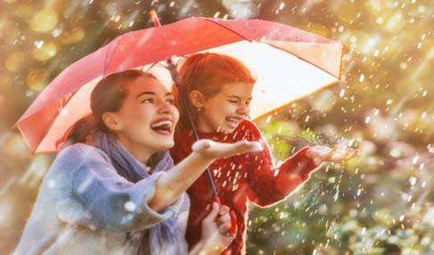 Einfach zeitlos: Eine Mutter steht mit ihrer Tochter unter einem großen Regenschirm von dem regen abperlt.