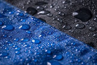 Regentropfen auf einer blau-schwarzen Ski Jacke.