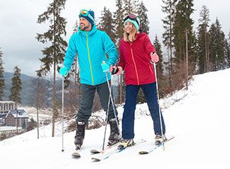 Eine Frau in einer roten Ski Jacke ist mit ihrem Mann in einem Ski Gebiet.