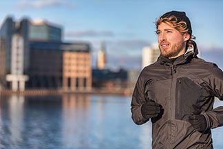 Ein Mann läuft in einer schwarzen Sportjacke vor einem Fluss.
